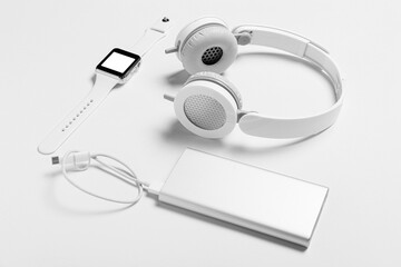 Smart watch, headphones and power bank on white background