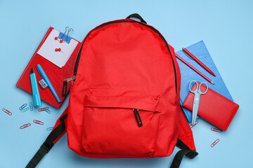 Set of stationery with backpack on color background