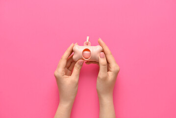 Woman holding dispenser with pet waste bags on pink background, closeup