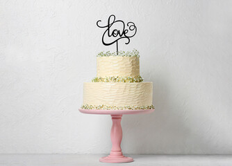 Dessert stand with beautiful wedding cake and topper with word LOVE on table