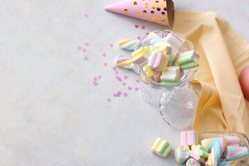 Composition with tasty marshmallows, party hat and confetti on light background