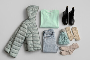Warm female clothes, accessories and boots on light background