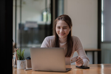 Fototapeta premium Portrait smiling asian woman resting and shopping online at home, Happy woman using laptop and credit card for online shopping. Online payment concept.