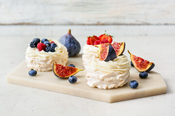 Board of tasty Pavlova cakes with fresh berries on light background