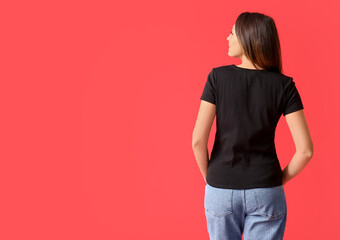 Young woman in blank t-shirt on color background, back view