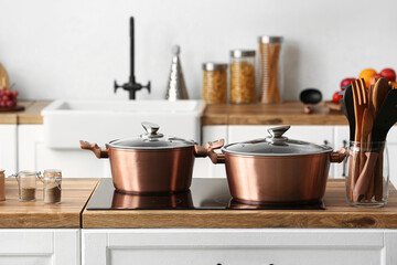 Fototapeta na wymiar Shiny copper cooking pots on stove in kitchen