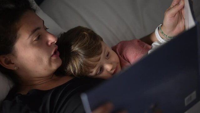 Mother telling bedtime story to todlder mom holding book night routine