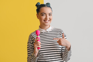 Beautiful young woman with vibrator from sex shop on color background