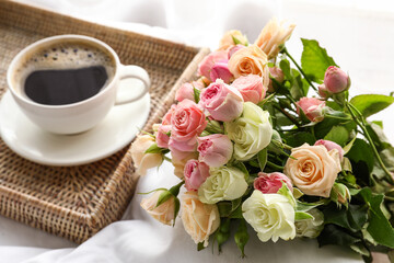 Fototapeta na wymiar Tray with cup of coffee and bouquet of beautiful roses on soft bed, closeup