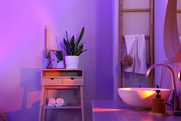 Interior of stylish bathroom with table, sink and neon lighting