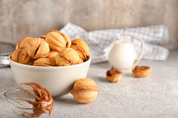 Bowl of walnut shaped cookies with boiled condensed milk on grey background
