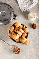 Bowl of walnut shaped cookies with boiled condensed milk on grey background