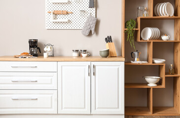 Interior of light kitchen with wooden shelving unit and pegboard