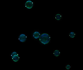 Many beautiful soap bubbles on dark background