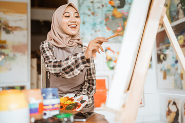 muslim painter is painting in her workshop excitedly