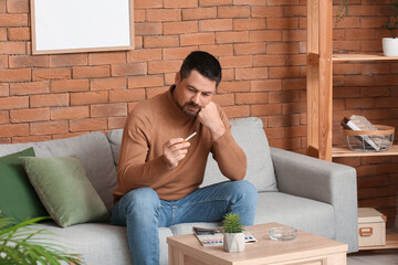 Thoughtful man with cigarette at home. Concept of refusing from bad habit