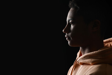 Silhouette of African-American teenage boy in hoodie on black background © Pixel-Shot