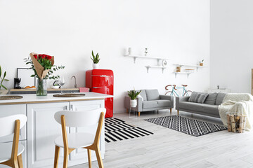Interior of modern kitchen with counters, sofas and red fridge