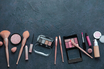 Set of decorative cosmetics with makeup brushes on dark background