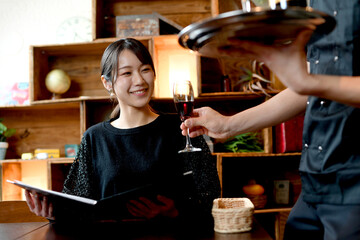 飲食店（レストラン）でワインを注文するアジア人の若い女性