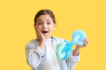 Surprised little girl with blue Pop Tubes on yellow background