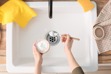 Woman with spoon and cleaning powder over ceramic sink, closeup