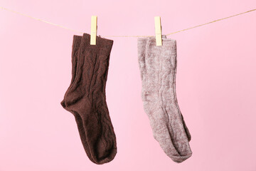 Socks hanging on rope against pink background