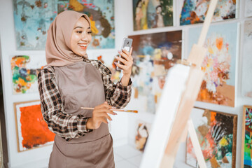 muslim female artist looking for inspiration from her mobile phone