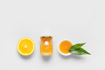 Composition with tasty orange jam and leaves on blue background