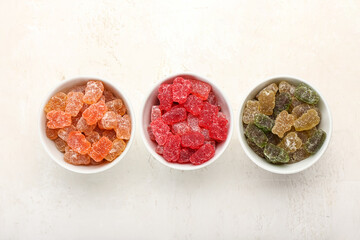 Bowls with tasty jelly bears on light background