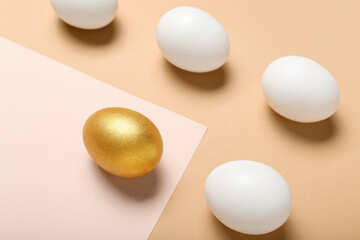 Golden Easter egg among white ones on color background, closeup