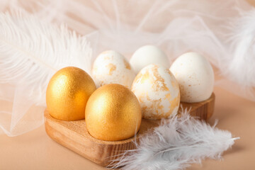 Holder with beautiful Easter eggs, feathers and cloth on color background, closeup