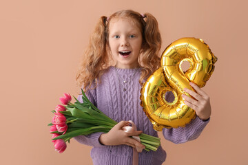 Little redhead girl with balloon in shape of figure 8 and tulips on beige background. International Women's Day