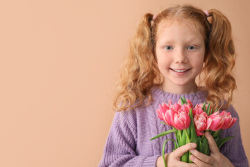 Little redhead girl with bouquet of tulips on beige background. International Women's Day