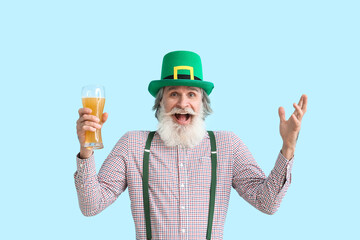 Happy senior man with glass of beer on blue background. St. Patrick's Day celebration