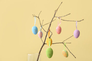 Composition with different Easter eggs hanging on tree branch against color background