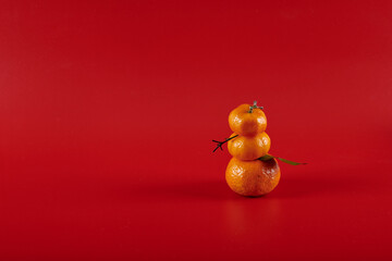 snowman made of three tangerines on a red background
