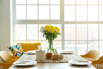 Dining table with setting and vase served for International Women's Day celebration in light kitchen