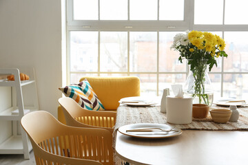 Dining table with setting and vase served for International Women's Day celebration in light kitchen