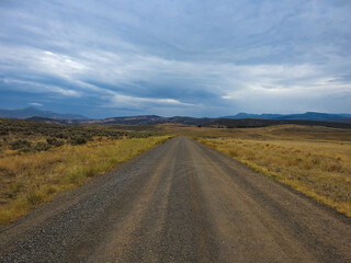 A Countryside Gravel Road Leading Down into Mountains on the Horizon