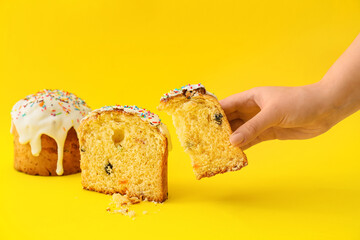 Woman holding piece of delicious Easter cake on yellow background