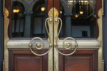 Vintage polished brass ornate door handles on an entrance door of a historic building. Martin Place