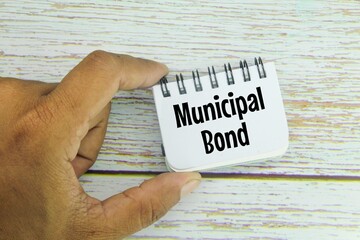 hand holding a notebook with the words MUNICIPAL BONDS