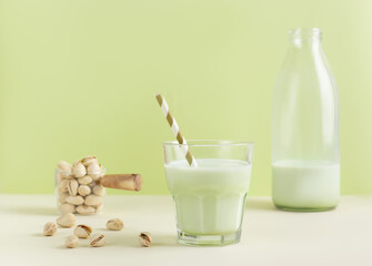 Pistachio milk the glass next to bottle of milk and pistachios