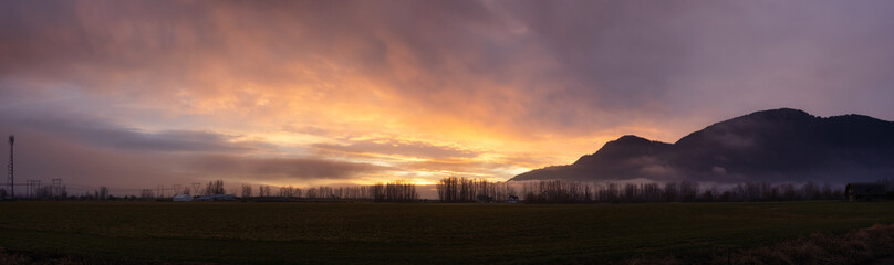 Panoramic View of Farm lands and Canadian Mountain Nature Landscape. Dramatic Winter Sunset. Located near Chilliwack and Abbotsford, British Columbia, Canada.