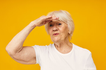 Photo of retired old lady in casual t-shirt gestures with his hands yellow background