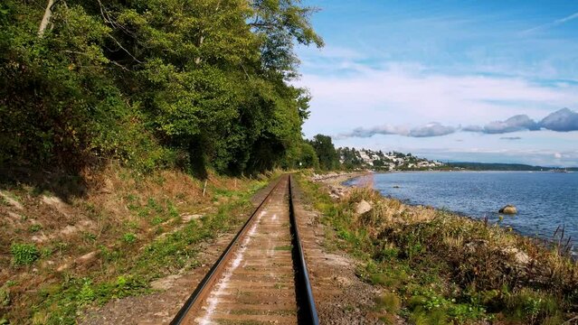 4k Drone footage of a locomotive eye view moving forward on the train tracks along the ocean coastline. Someplace in western Canada.