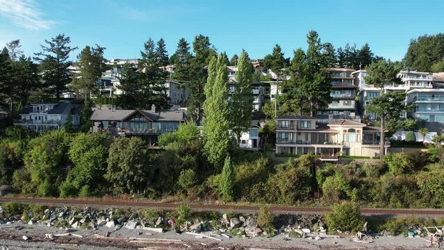4K Aerial drone shot of White Rock Beach coastline in British Columbia, Canada. Blue Pacific Ocean with waves coming in and beach with nice houses in the background.