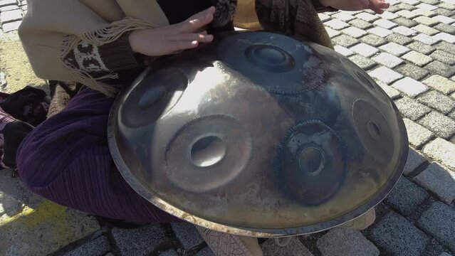 A street performer playing a hand pan instrument, also known as Hang.
