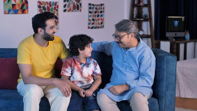 Handsome father and an old man hugging an adorable child at home - three generations  Indian joint family  love and care. Grand father  son  and grandson spending time together - leisure time  fami...
